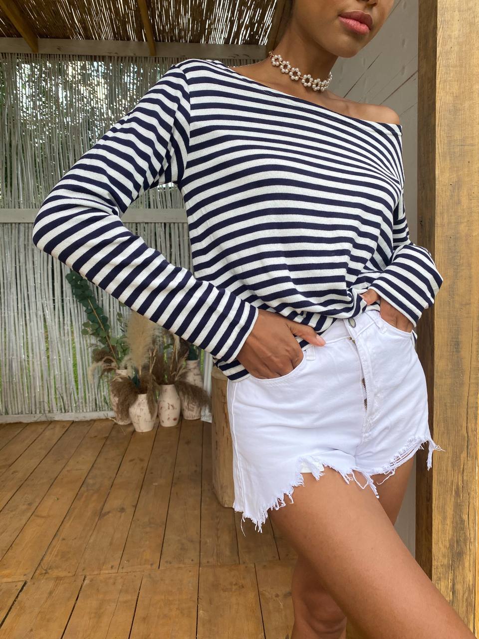 Person wearing a black and white striped long-sleeve top and white shorts outdoors.