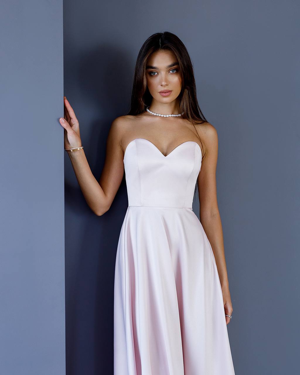 Woman wearing a strapless white dress against a gray background