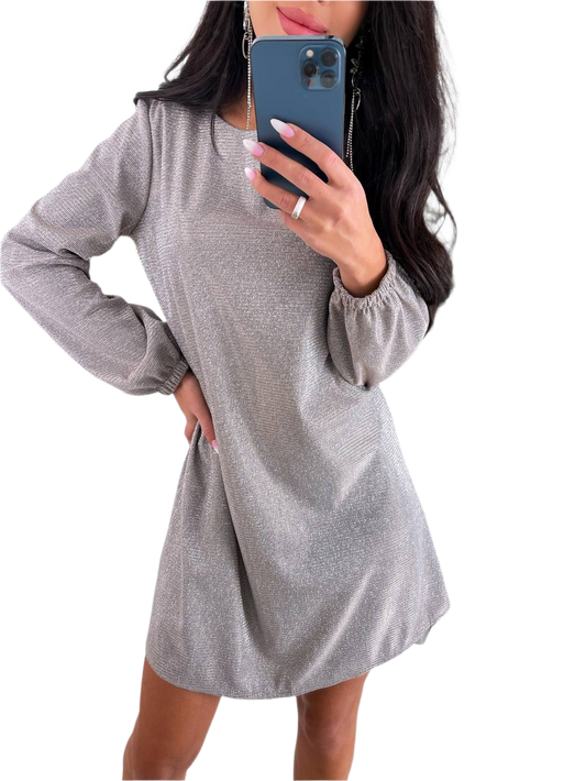 Woman wearing a gray long-sleeve dress holding a phone on a white background