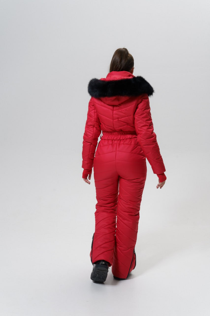 Person wearing a red snowsuit with black fur trim on a white background