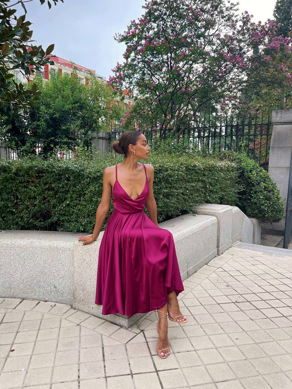 Woman in a magenta dress sitting on a stone bench outdoors.