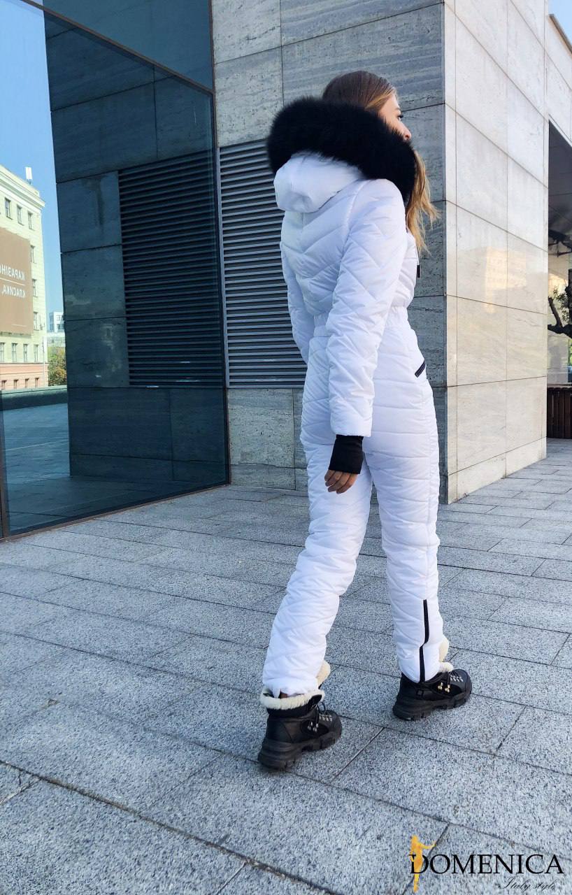 Person wearing a white puffer suit with a fur-lined hood in an urban setting.