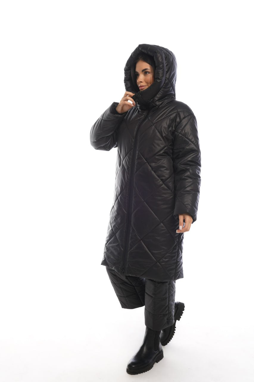Person wearing a black quilted jacket and pants on a white background