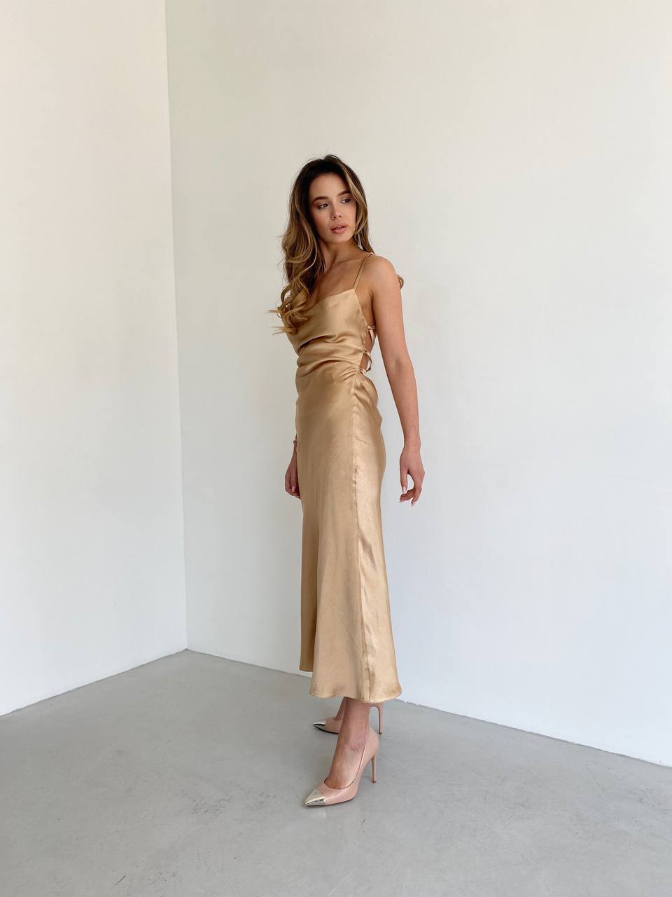 Woman wearing a gold satin dress against a white background