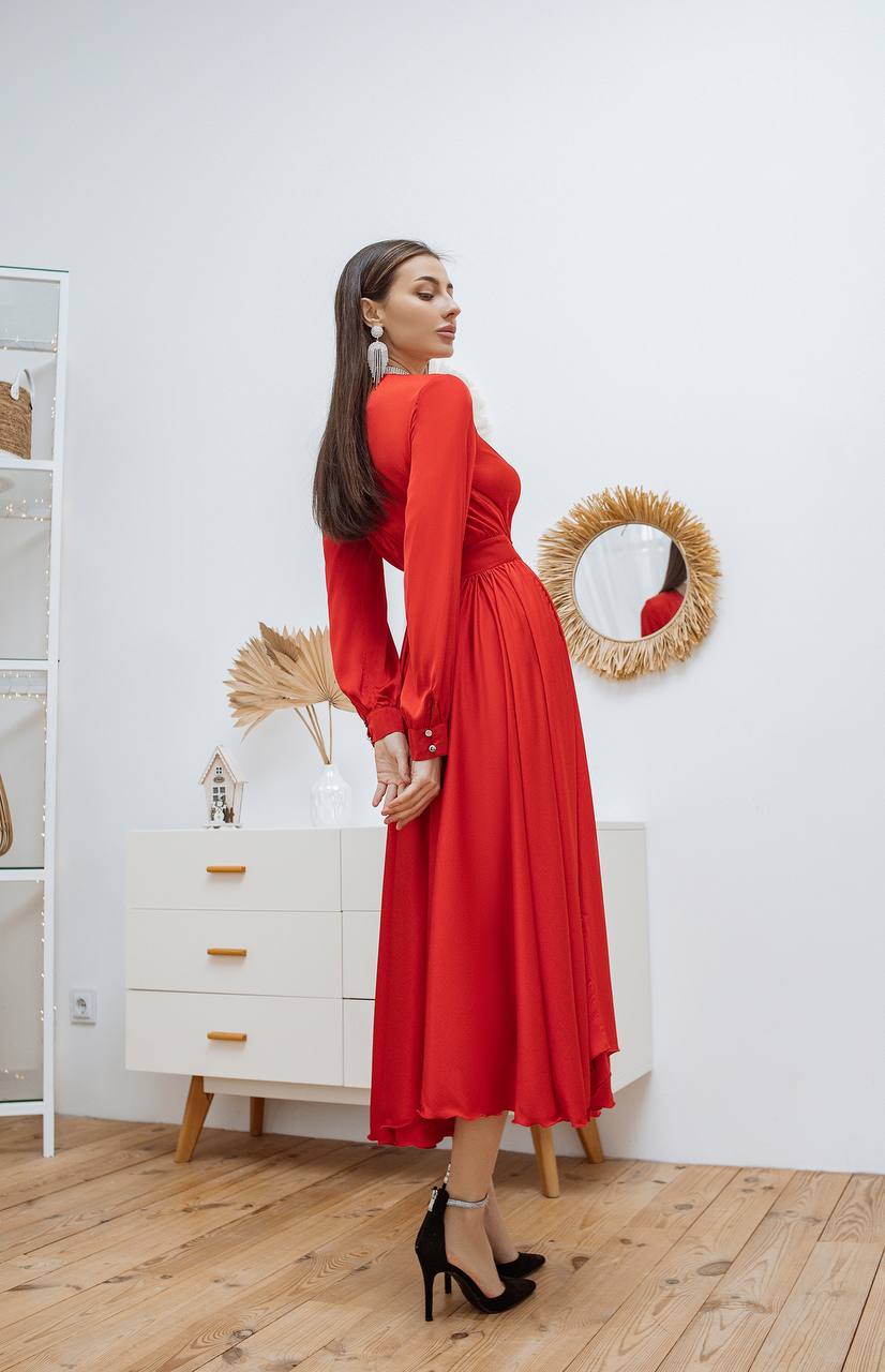 Woman in a red dress standing in a room with a white dresser and decorative mirror.