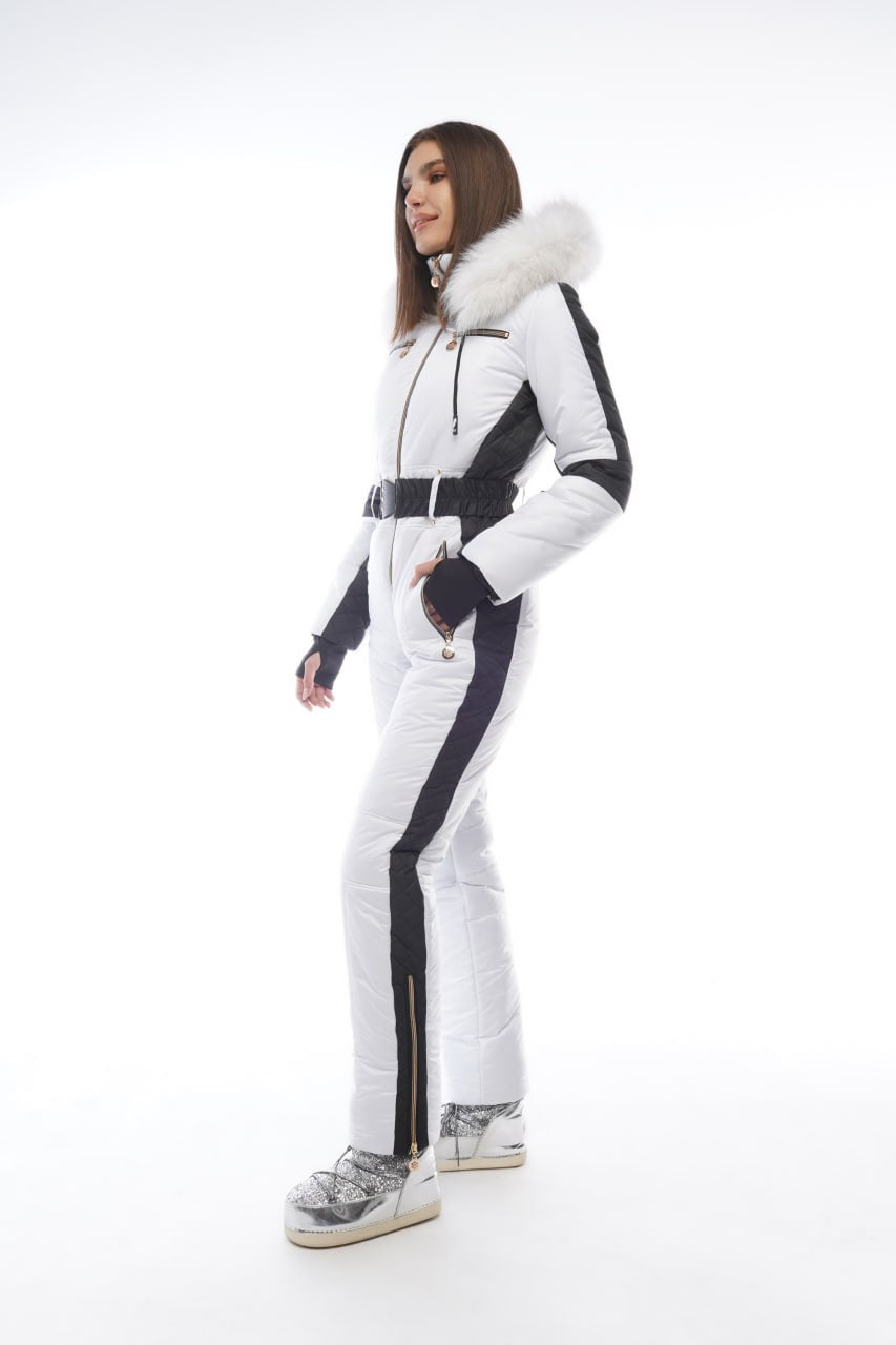 Woman wearing a white and black ski suit with fur trim on a white background