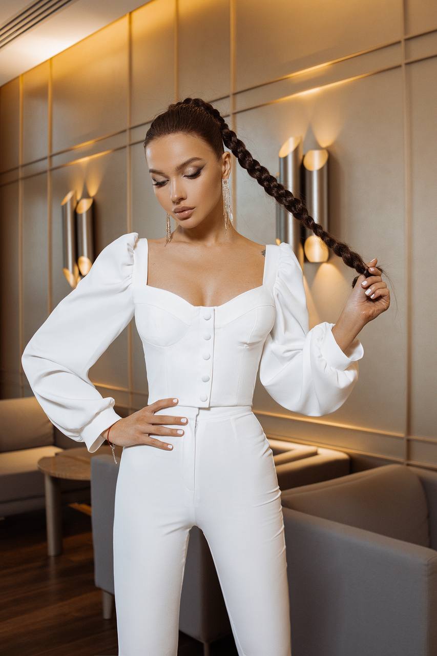 Woman in a white outfit posing in an elegant interior setting