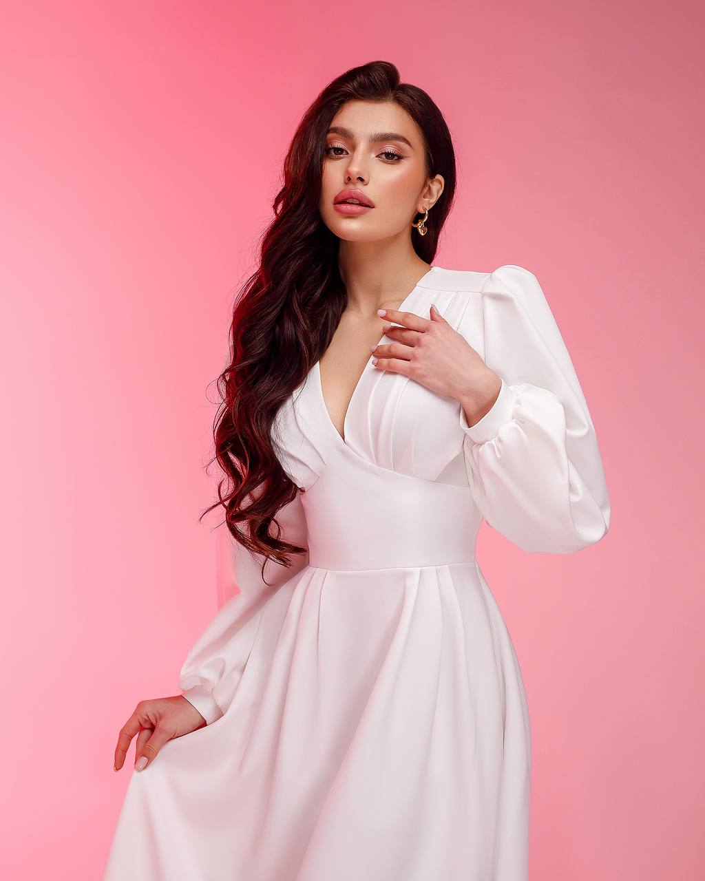 Woman in a white dress against a pink background