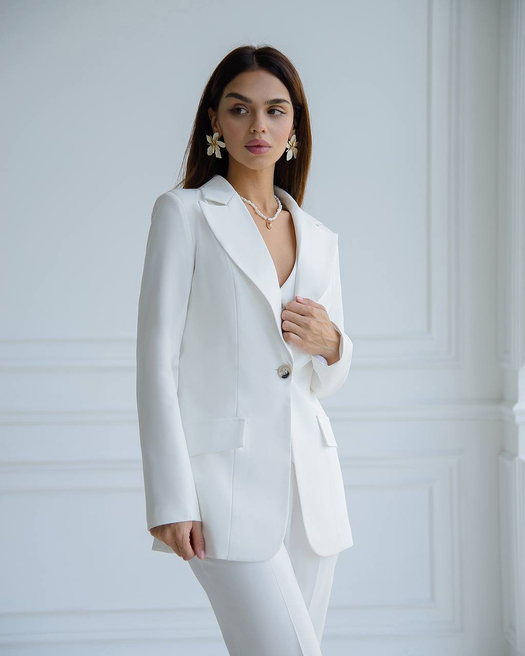 Woman wearing a white suit against a light gray background