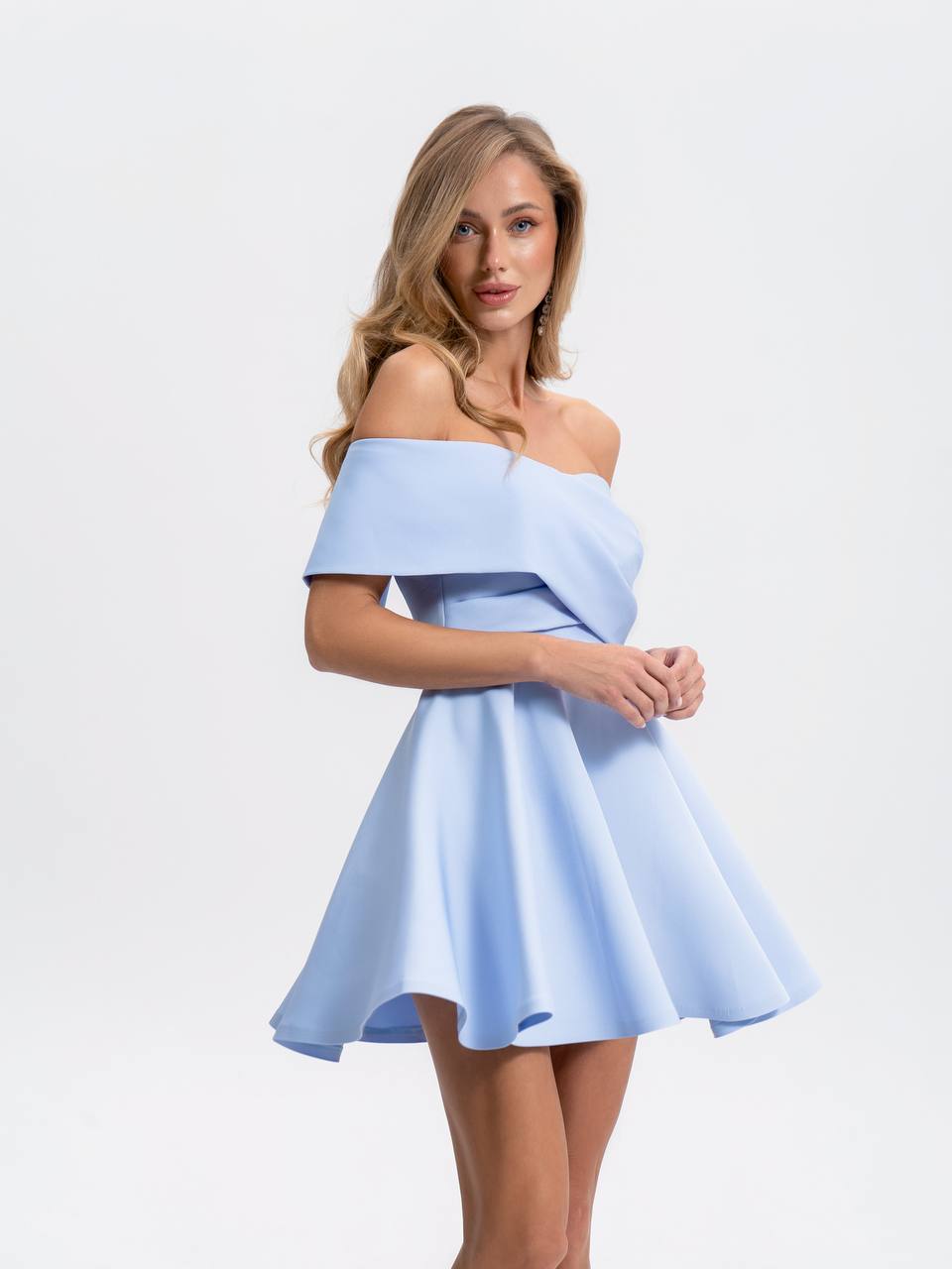 Woman wearing a light blue off-shoulder dress on a white background