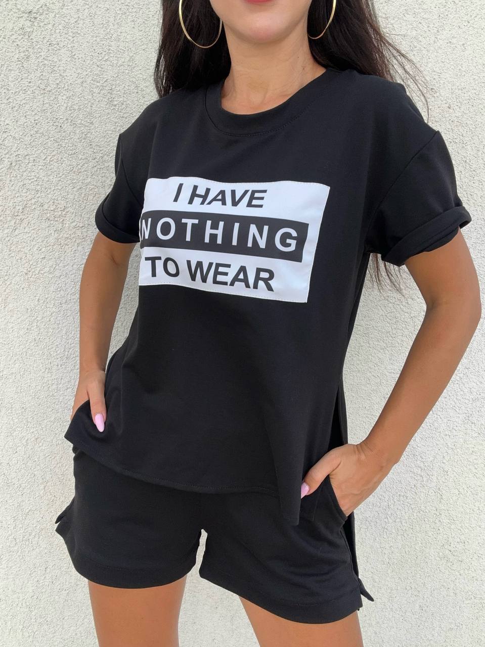 Person wearing a black t-shirt with text and black shorts against a light background