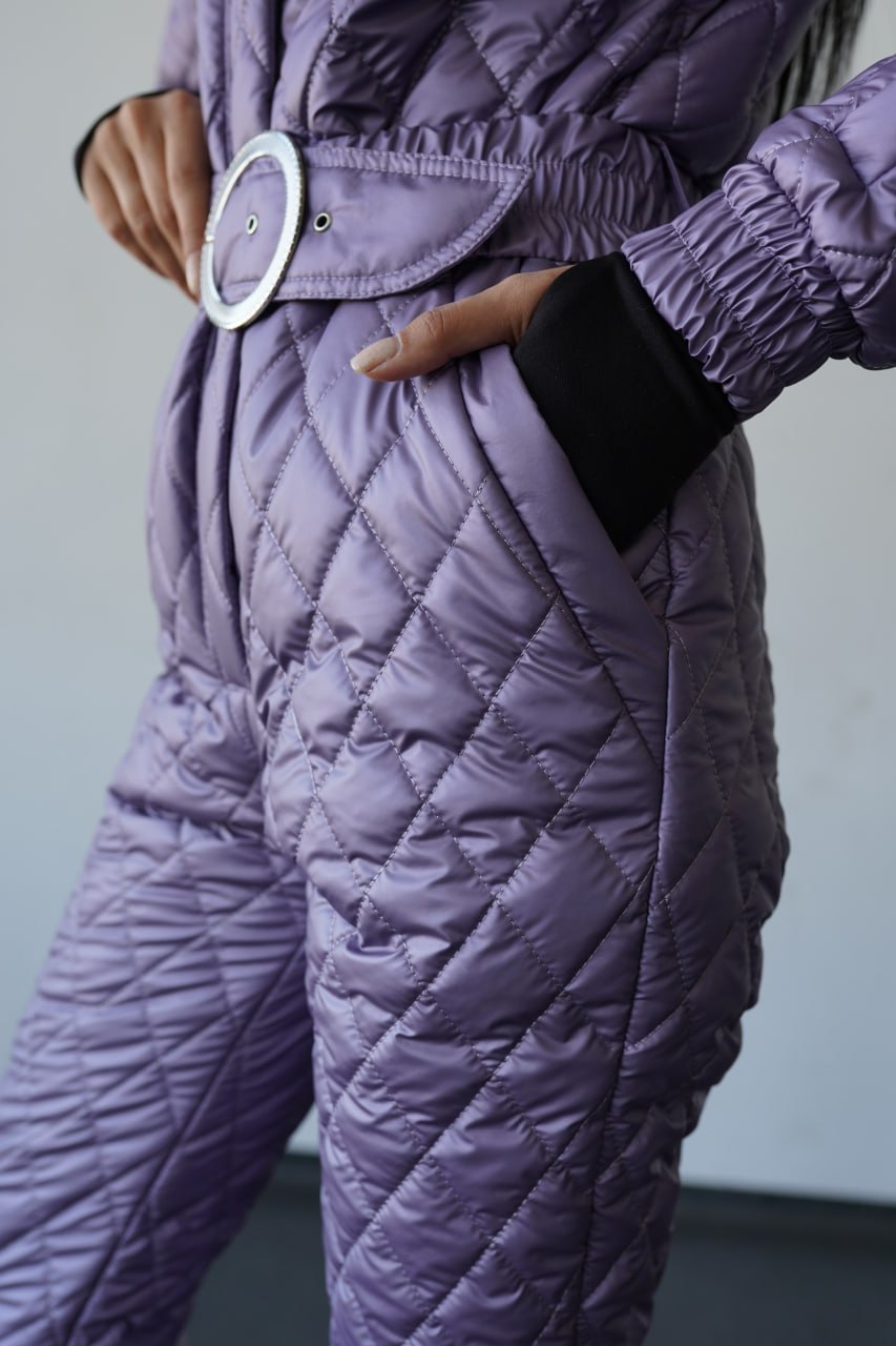 Person wearing a quilted purple outfit with a belt and black glove.