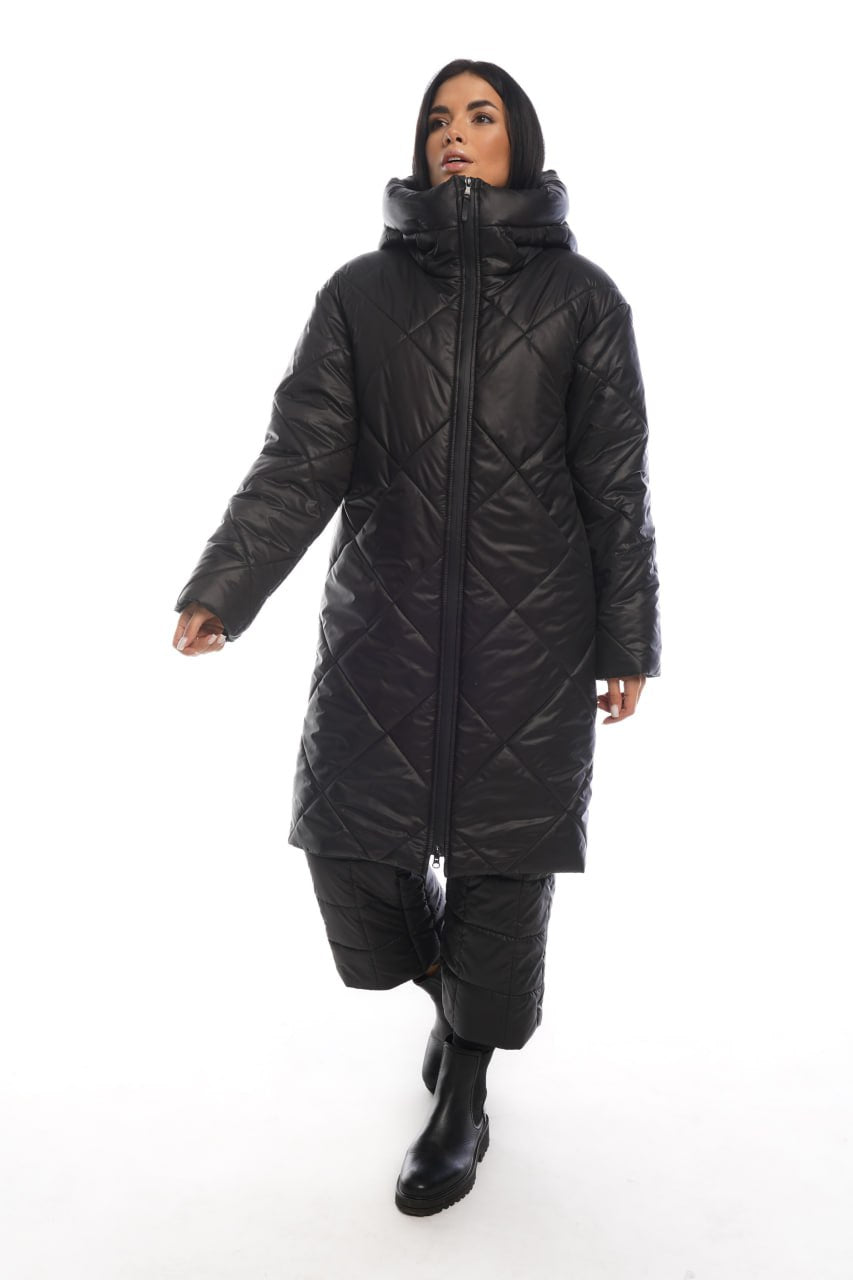 Person wearing a long black quilted coat on a white background