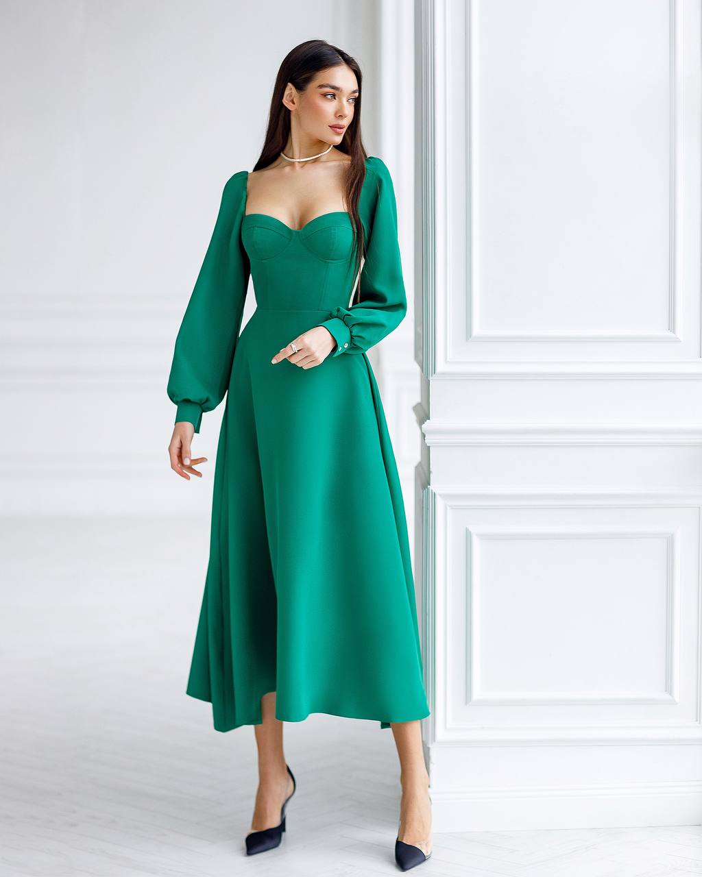 Woman wearing a green dress against a white wall