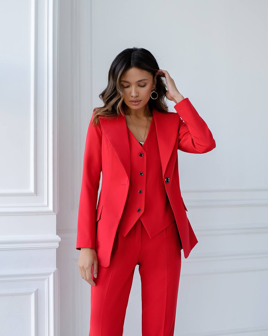 Woman wearing a red suit against a white wall