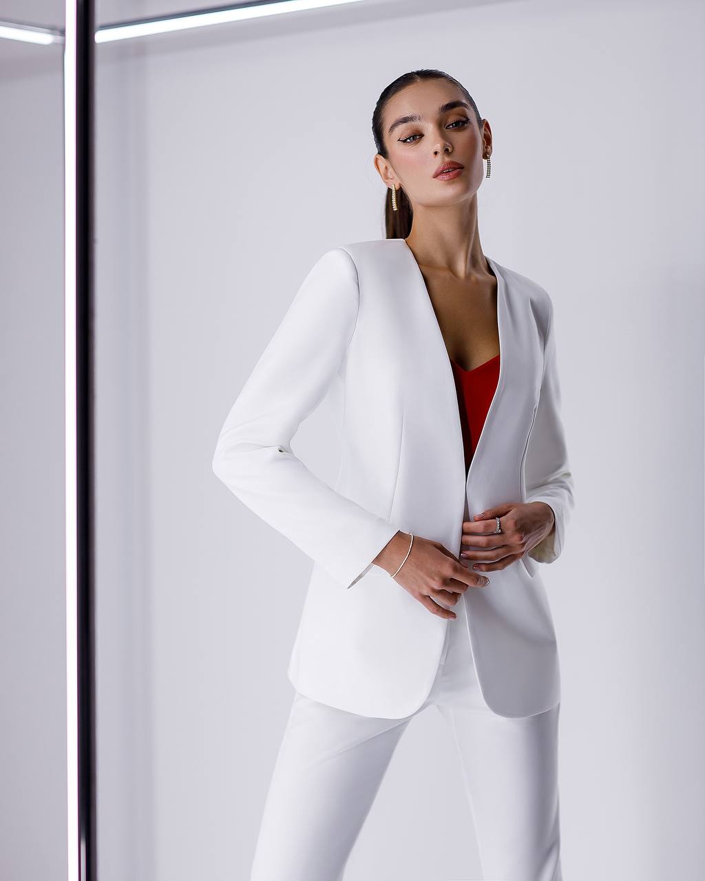 Woman wearing a white suit with a red top against a white background