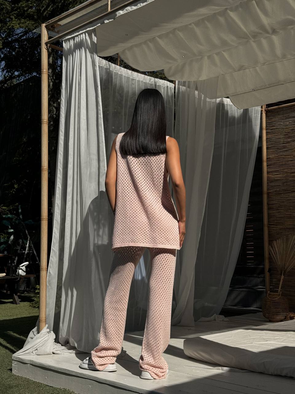 Woman in a pink outfit standing in front of a white curtain outdoors