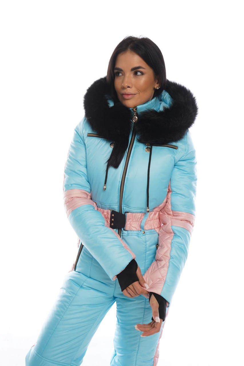 Woman wearing a light blue and pink snowsuit with black fur trim on a white background