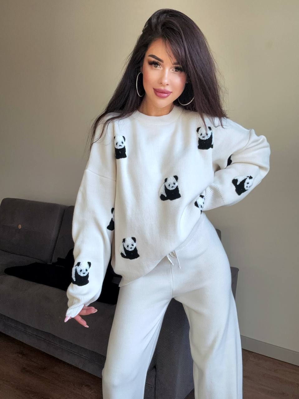 Woman wearing a white sweater with panda patterns in a living room.