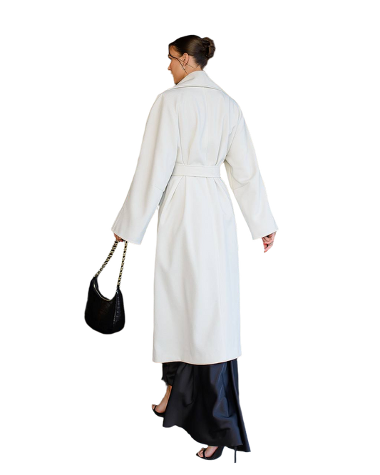 Woman wearing a white coat and black skirt with a black handbag on a white background