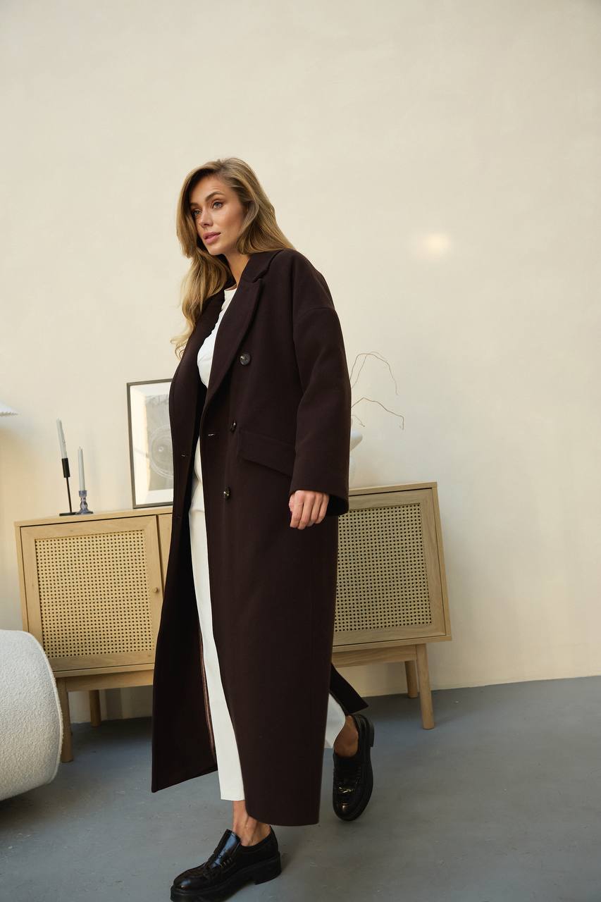 Woman wearing a long dark coat in an indoor setting