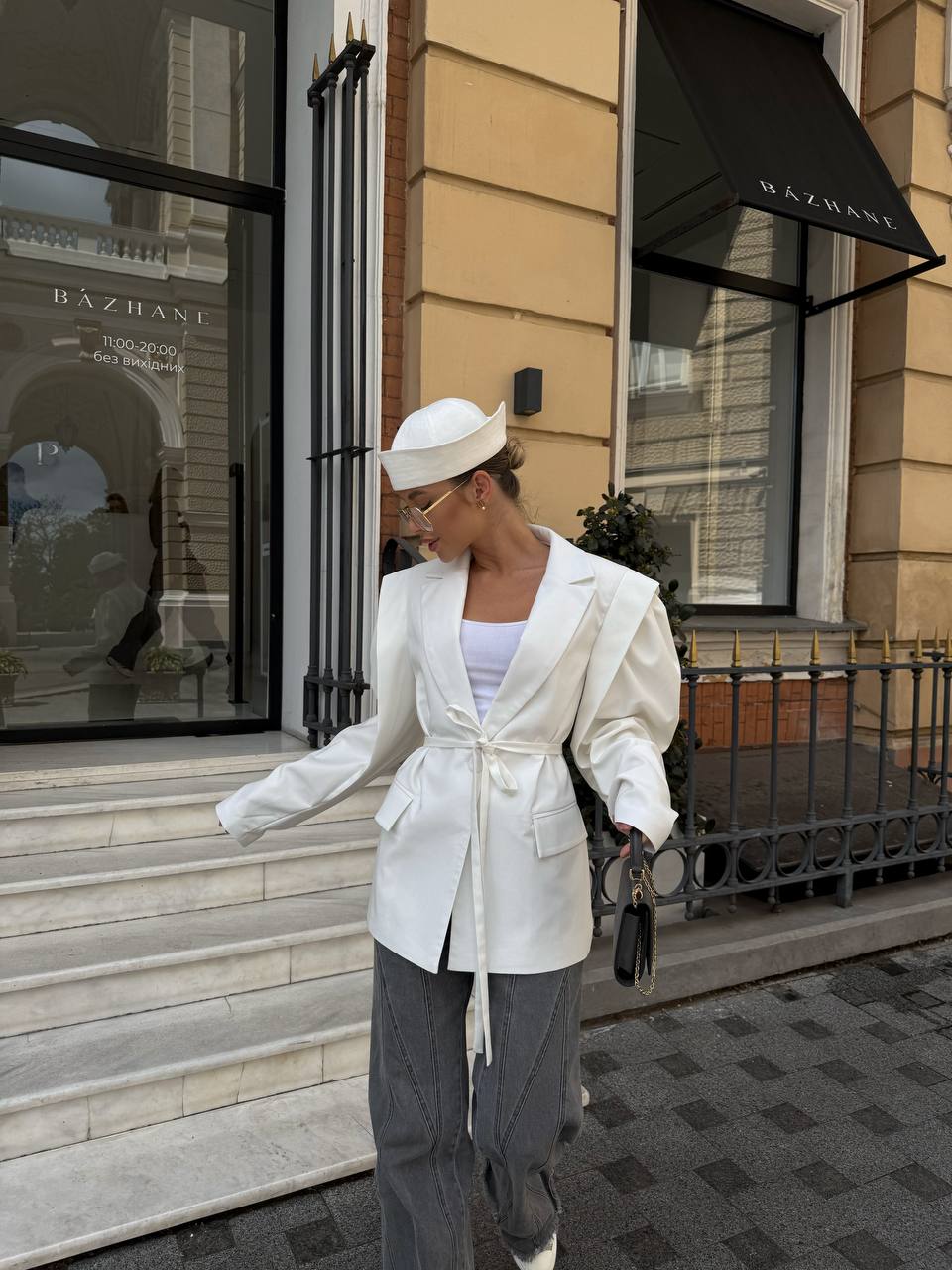 Woman in a white outfit walking on a city street with a building in the background