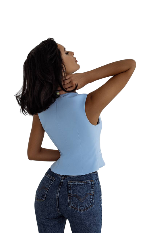 Woman wearing a light blue sleeveless top and dark blue jeans on a white background