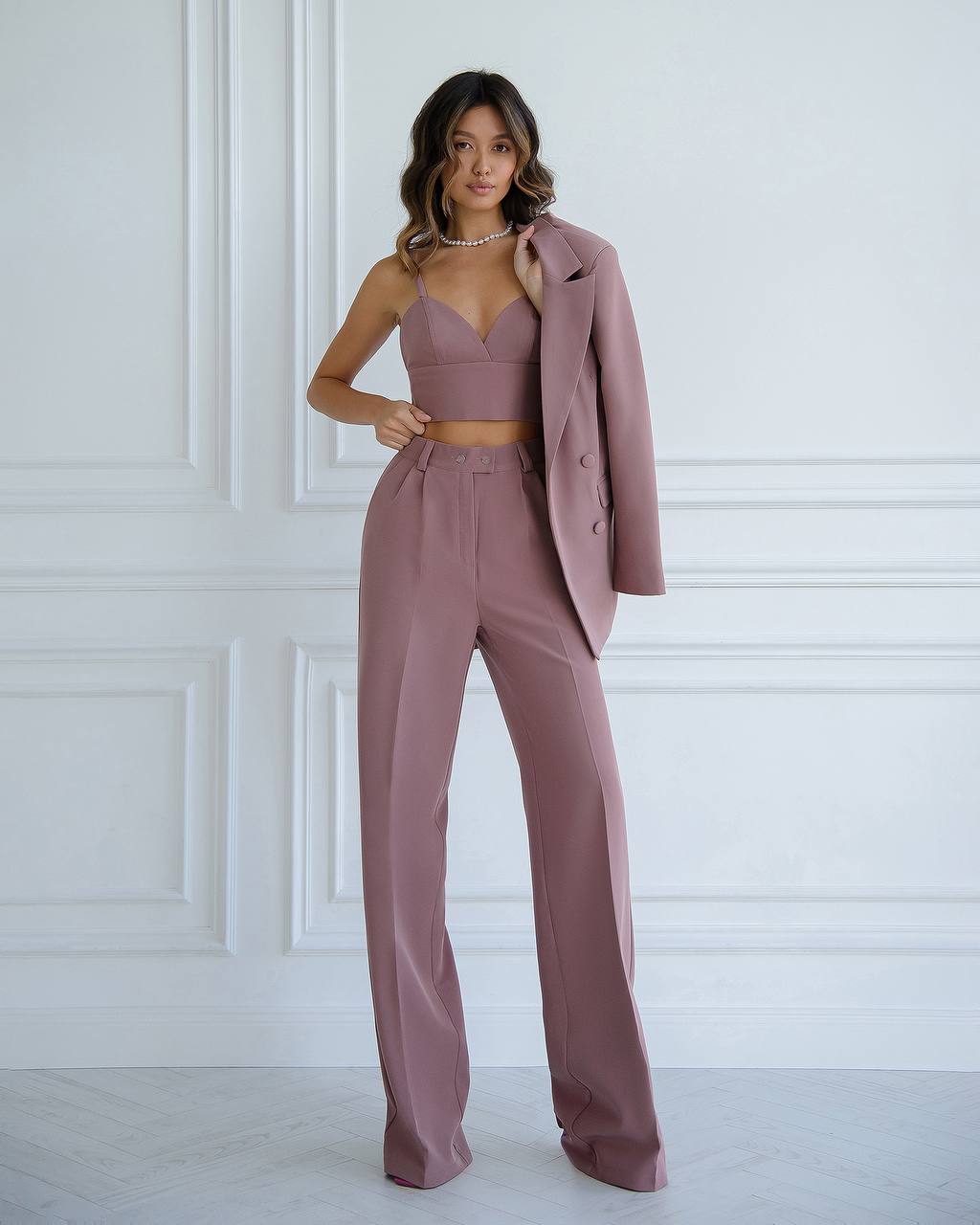 Woman wearing a mauve suit with a white wall background