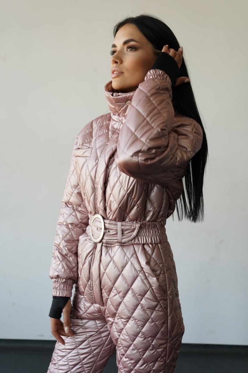 Woman wearing a quilted pink snowsuit against a plain background