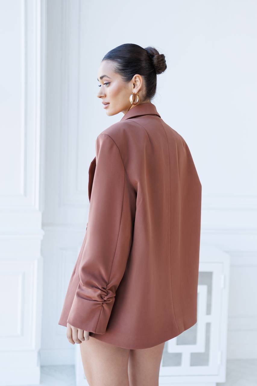 Woman wearing a brown coat in a minimalistic setting
