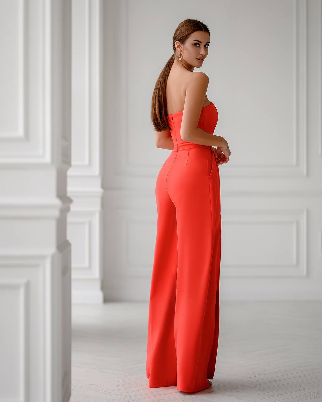 Woman wearing a red jumpsuit in a white room