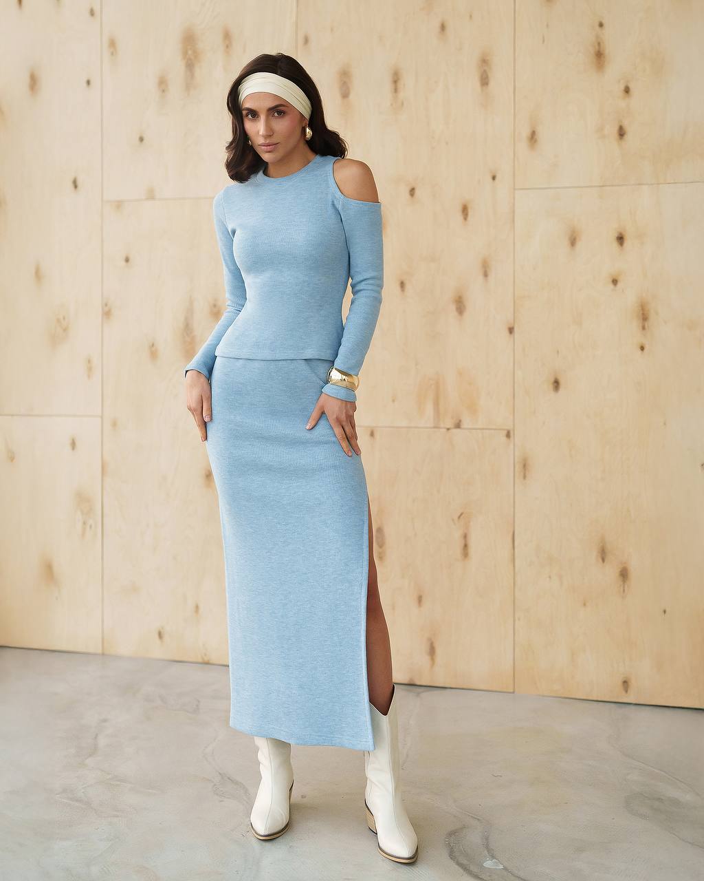 Woman wearing a light blue dress with a wooden wall background