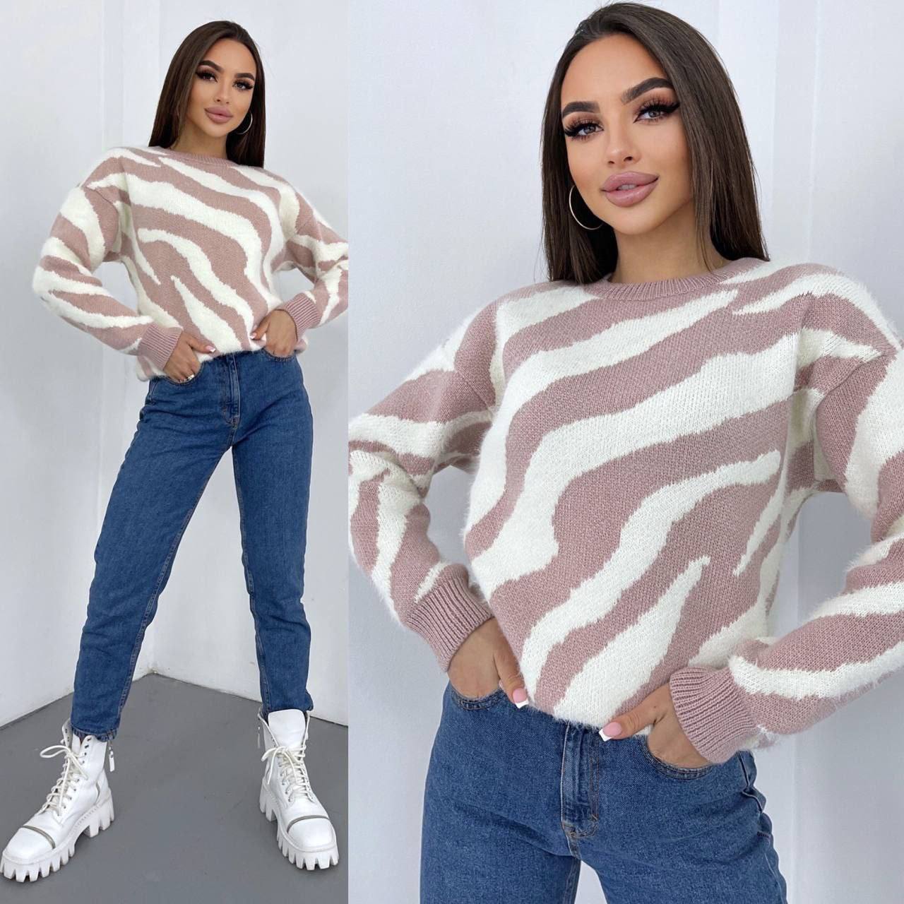 Woman wearing a zebra-striped sweater and blue jeans, posing against a white background.