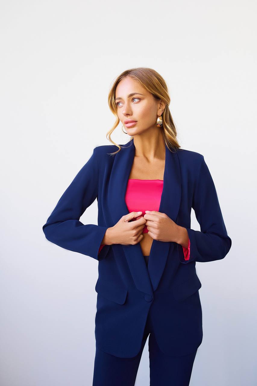 Woman wearing a navy blue suit with a pink top against a white background