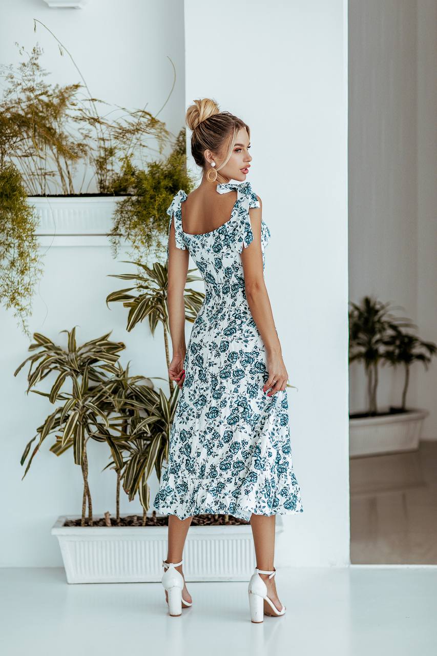 Woman in a floral dress standing in a room with plants