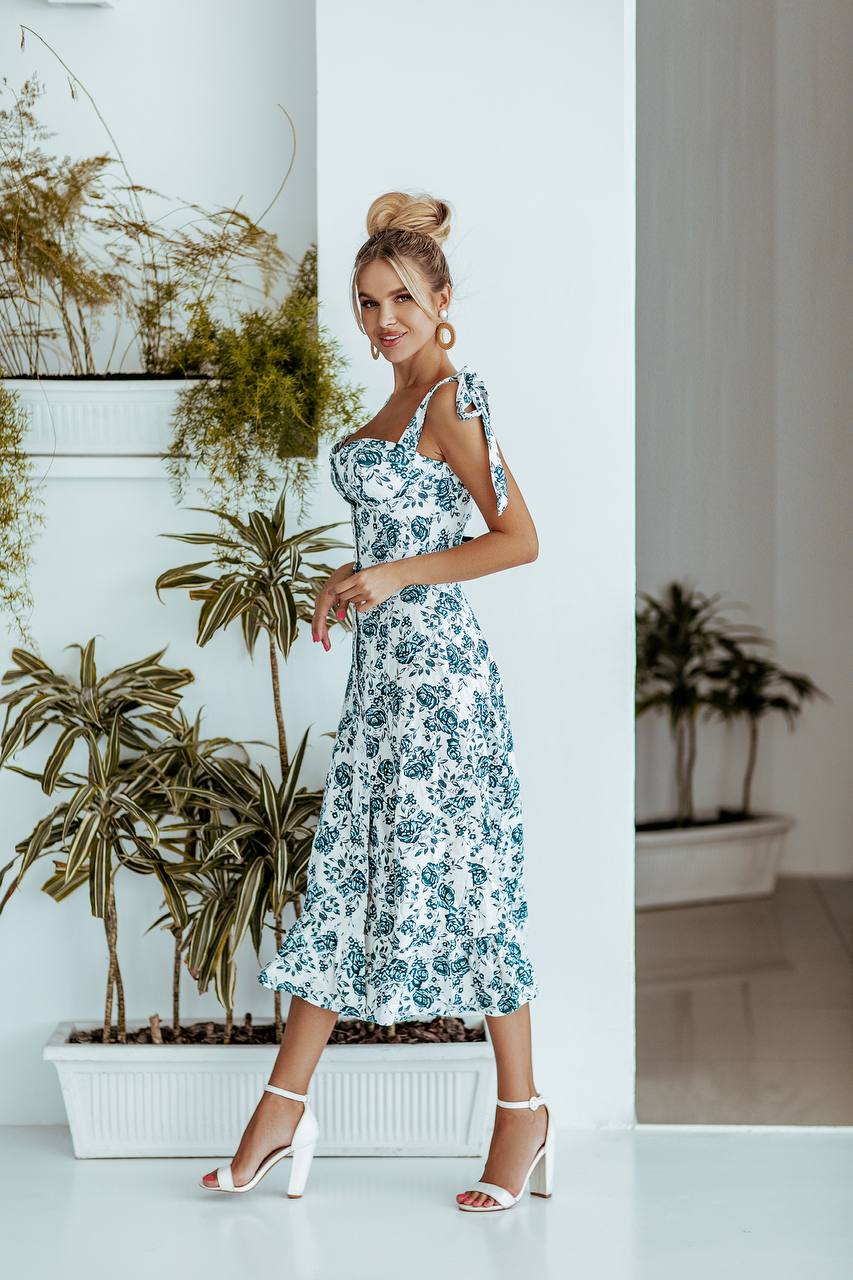 Woman in a floral dress standing in a room with plants