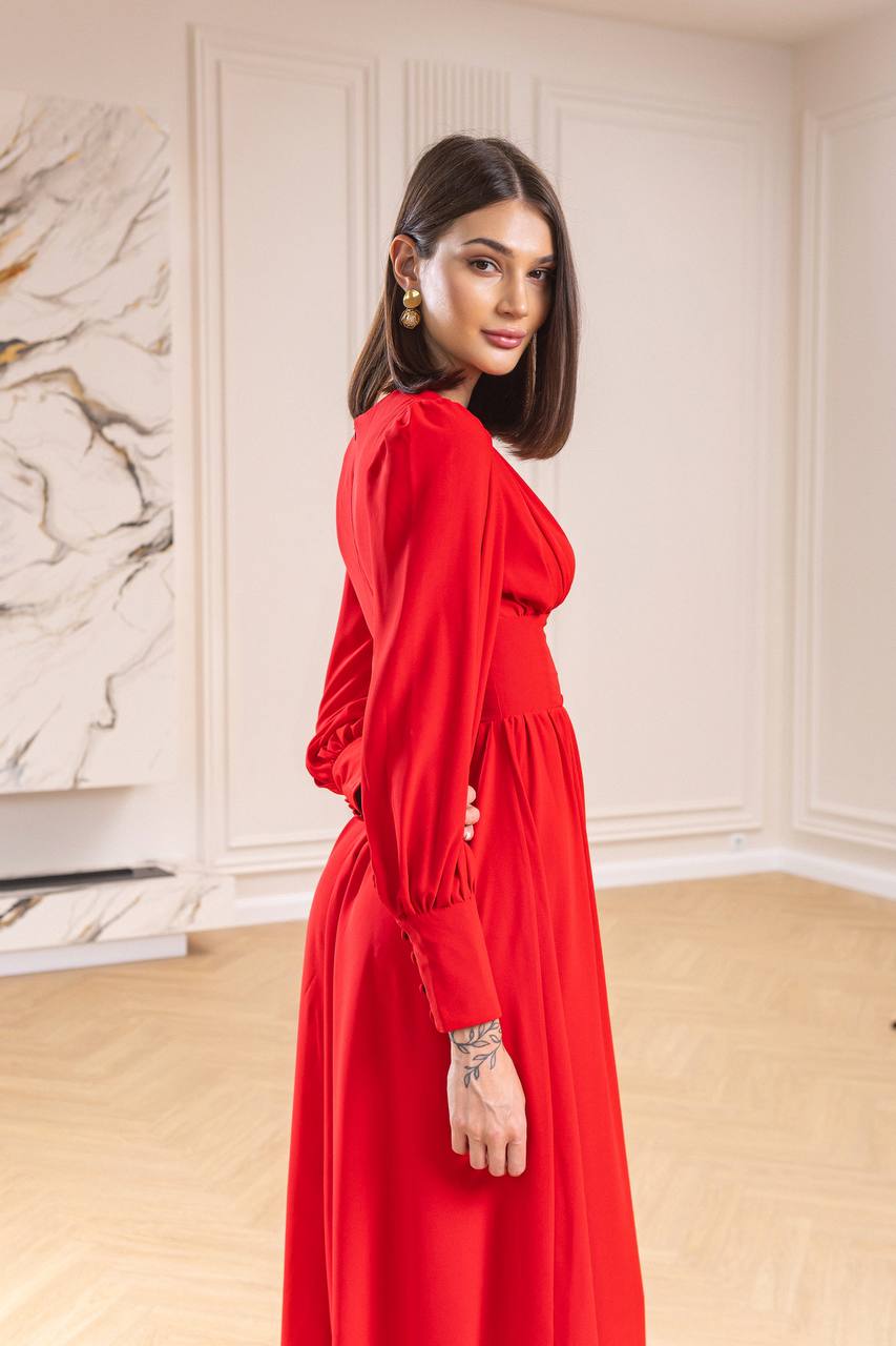 Woman in a red dress standing in a room with a marble wall.