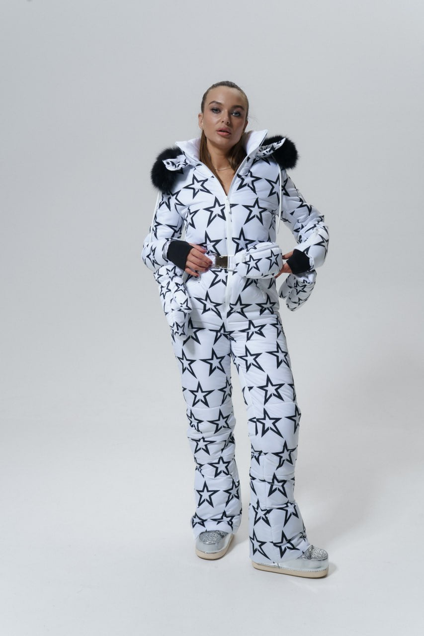Person wearing a white onesie with black star patterns on a plain background