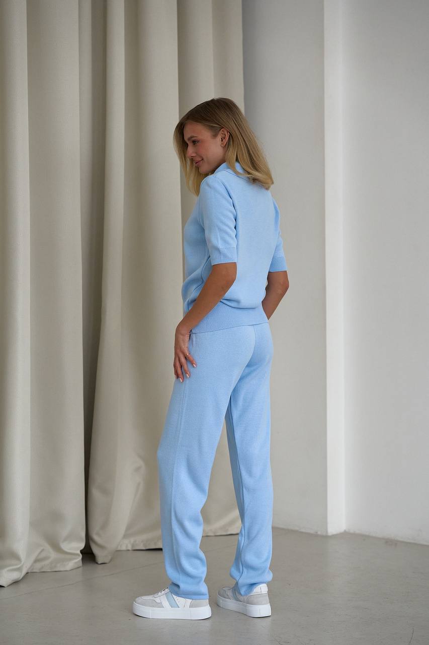 Woman wearing a light blue outfit standing against a neutral background