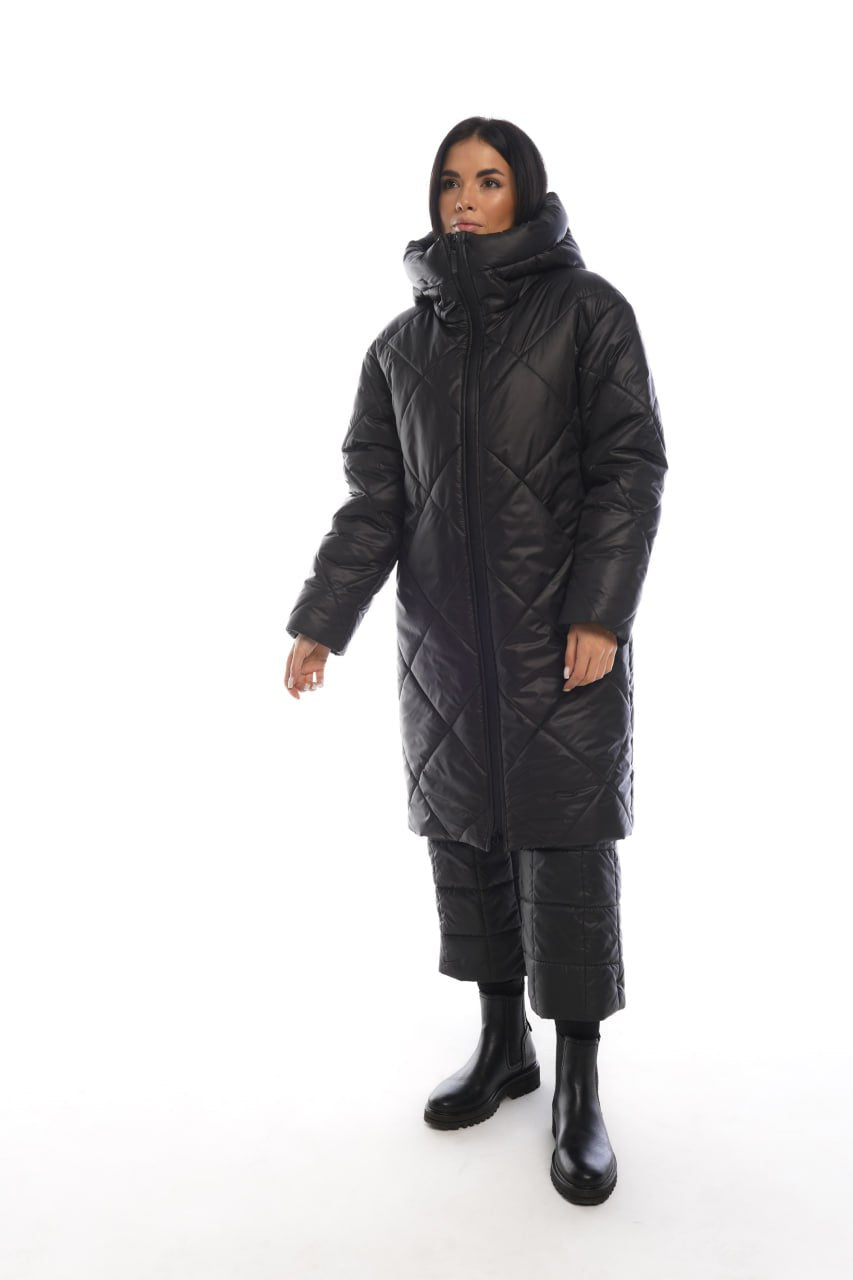 Person wearing a long black quilted coat on a white background