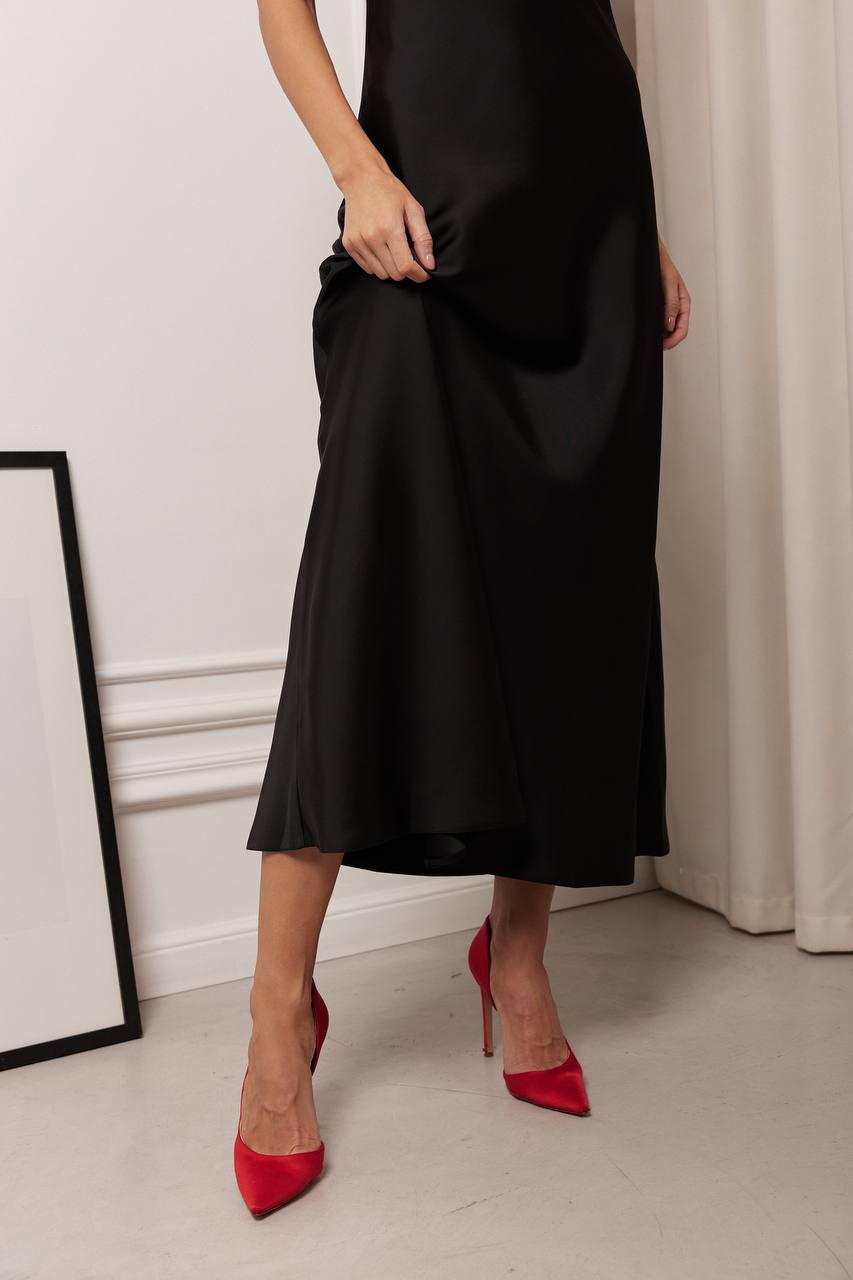 Person wearing a black dress and red high heels in a minimalistic setting