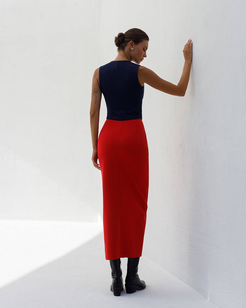 Woman wearing a navy top and red skirt against a white background
