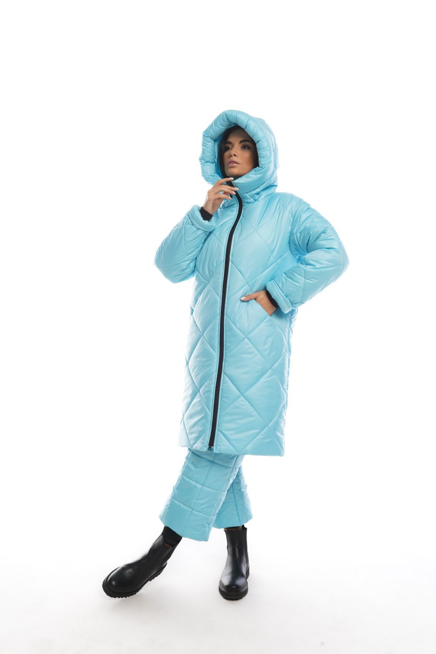 Person wearing a light blue quilted jacket and pants on a white background