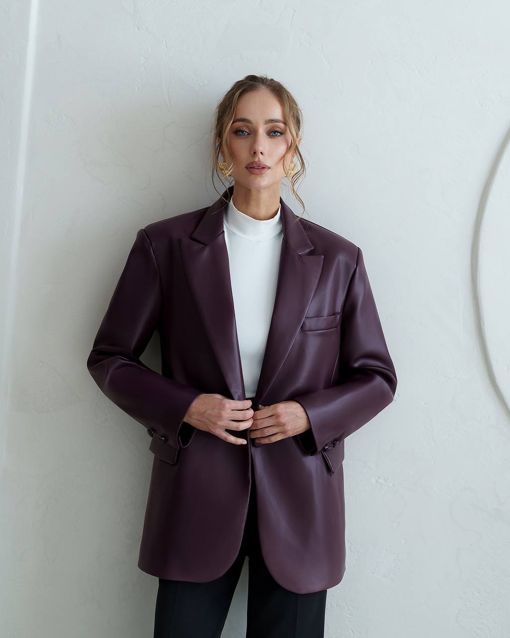 Woman wearing a purple blazer against a white wall