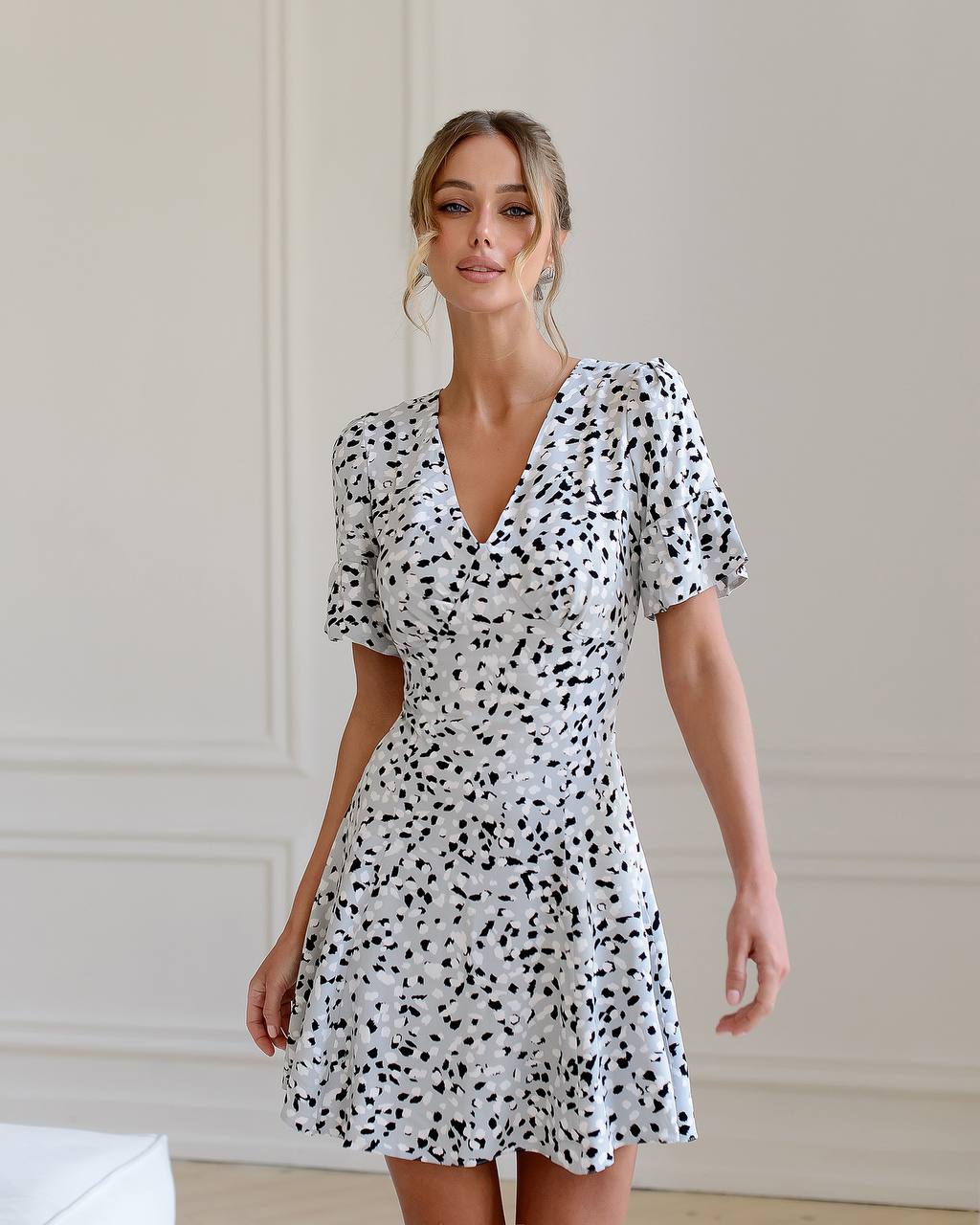 Woman wearing a black and white spotted dress against a plain background