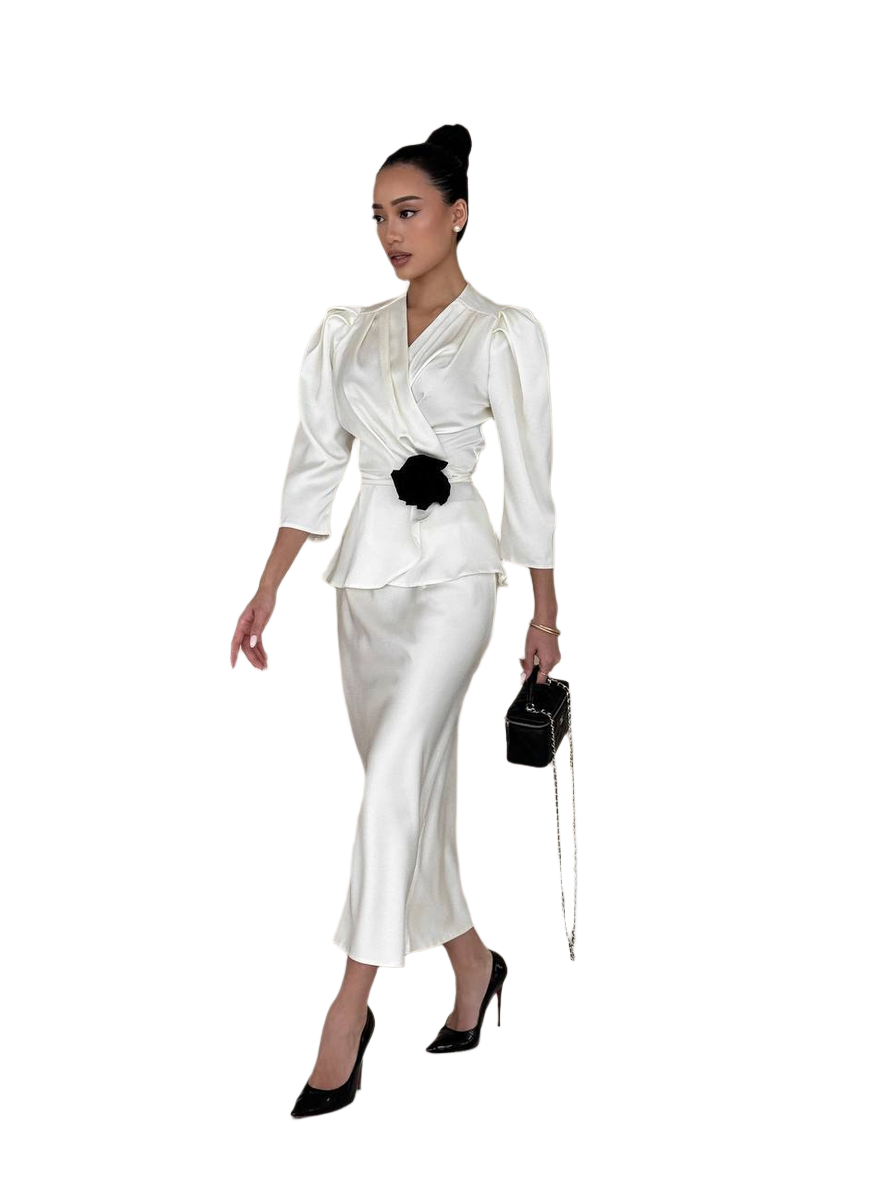 Woman wearing a white outfit with a black flower accessory on a white background