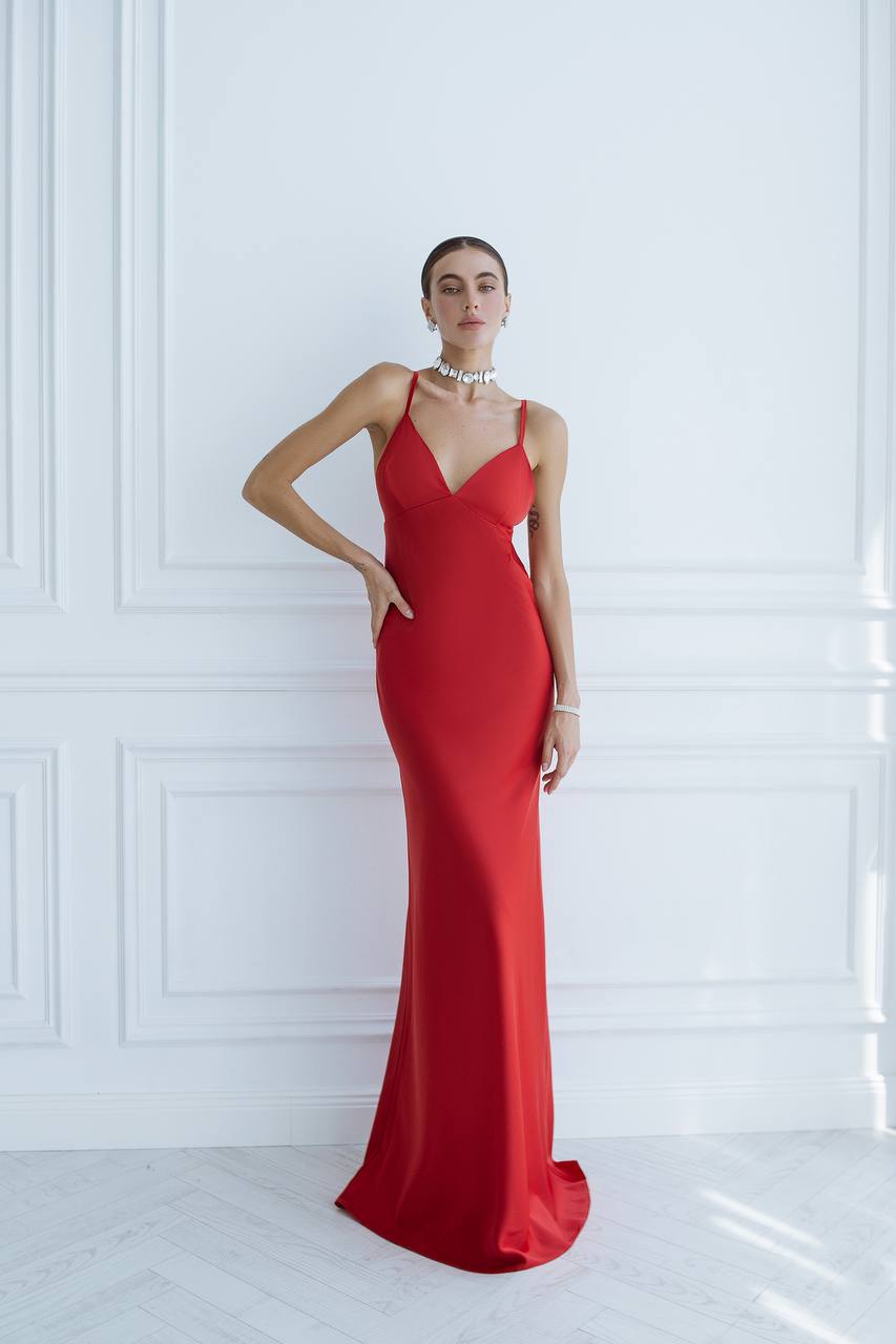 Woman wearing a red evening gown against a white wall