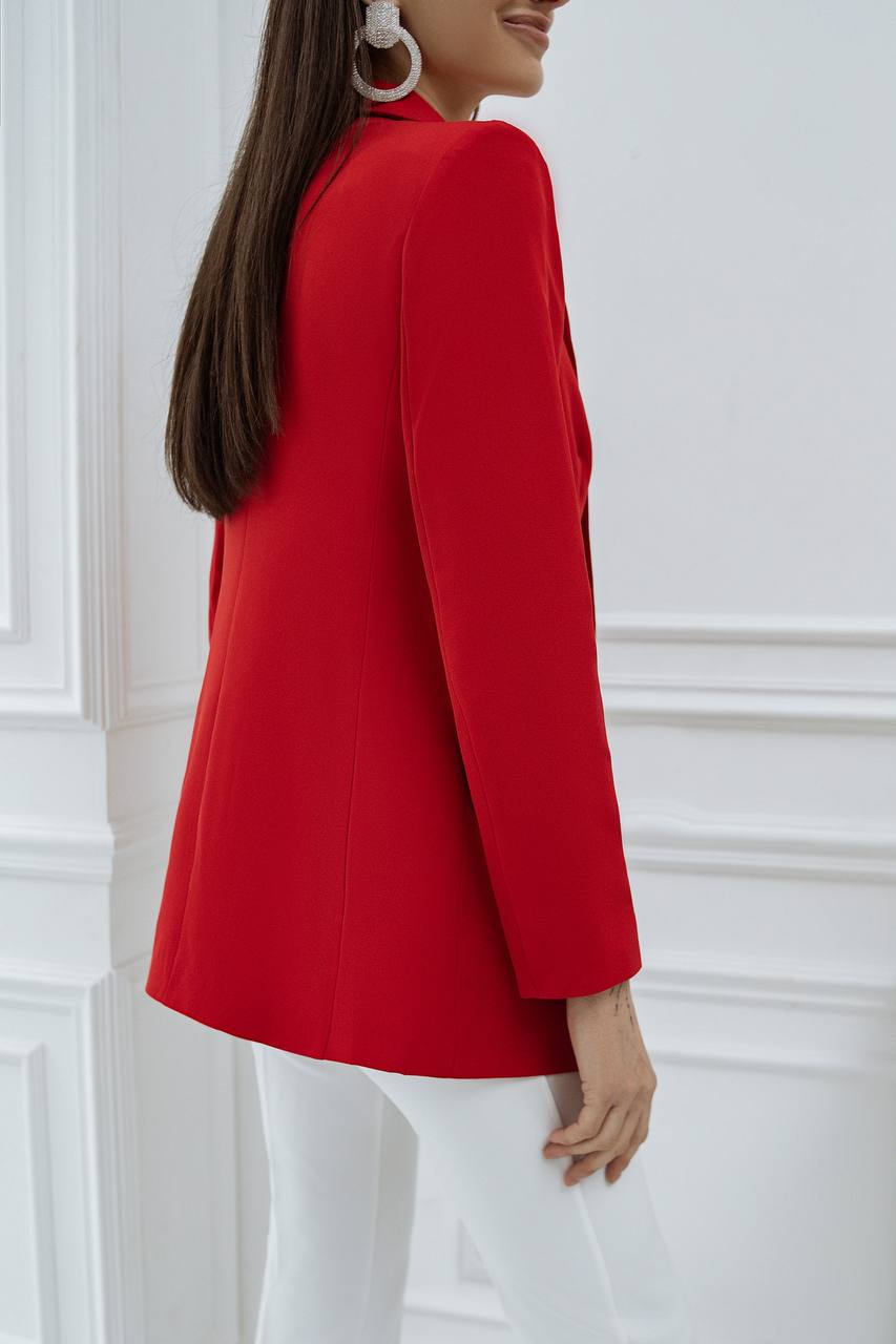 Person wearing a red blazer against a white wall