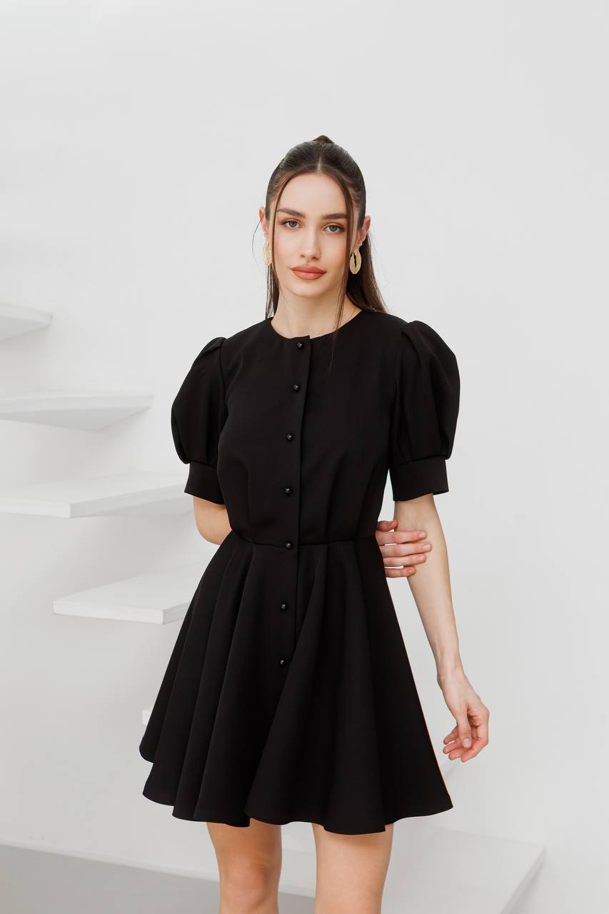 Woman wearing a black dress with puffed sleeves against a white background