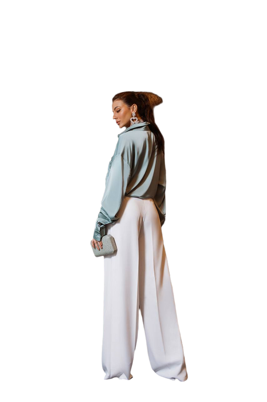 Woman wearing a light blue top and white pants on a white background